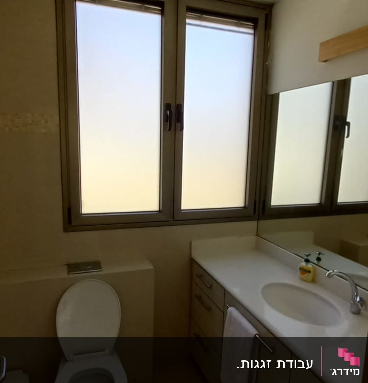 חלון זכוכית חלבית עם מסגרת מתכת בחדר אמבטיה